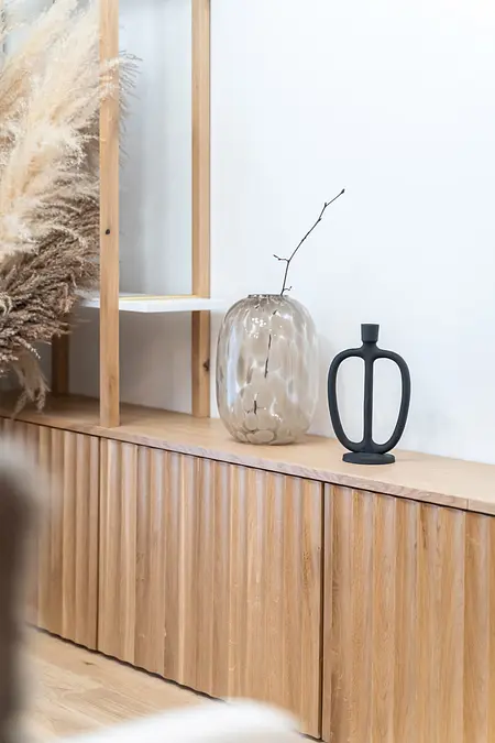 Stylowe wnętrze z boho i minimalistycznymi akcentami, prezentujące drewniane meble.