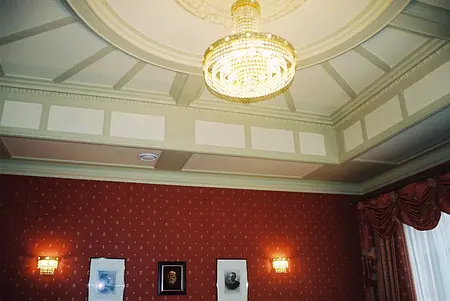 Stylowe wnętrze z czerwonymi ścianami i kryształowym żyrandolem, idealne do eleganckich aranżacji.