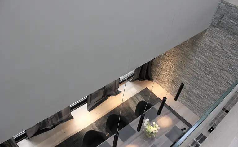 Wnętrze jadalni w stylu minimalistycznym z szarymi ścianami i drewnianym stołem, nowoczesne lampy.