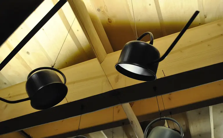 Nowoczesne oświetlenie w kuchni z drewnianym sufitem i industrialnymi lampami.