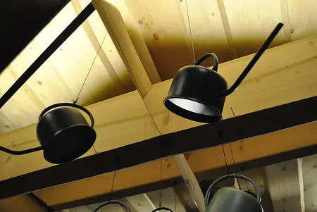 Nowoczesne oświetlenie w kuchni z drewnianym sufitem i industrialnymi lampami.