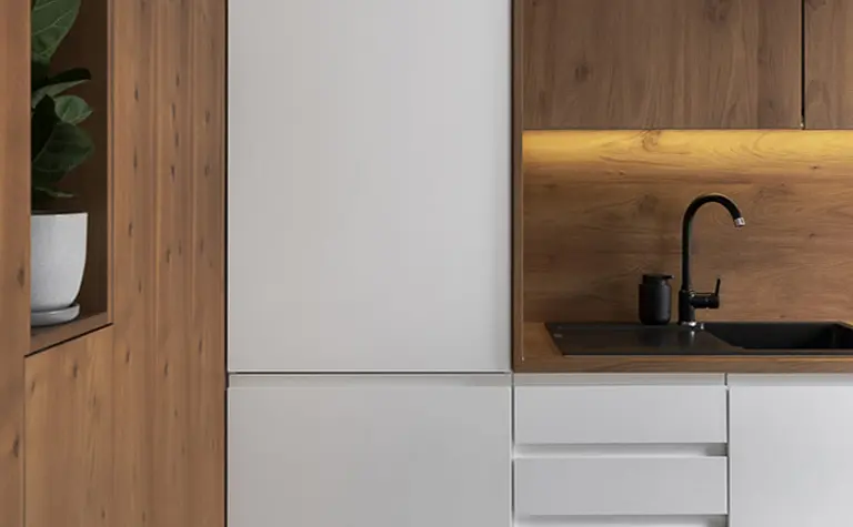Nowoczesna kuchnia z białymi szafkami i drewnianym wykończeniem, minimalistyczny design.