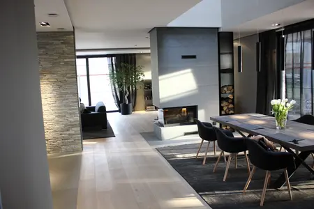 Stylowe wnętrze salonu z kominkiem, drewnianym stołem i minimalistycznymi akcentami.