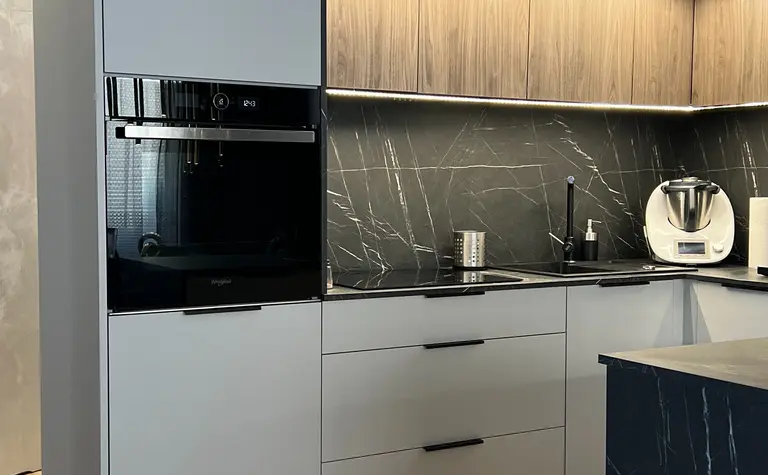 Nowoczesna kuchnia w stylu soft minimalizm z szarymi meblami i drewnianymi detalami.