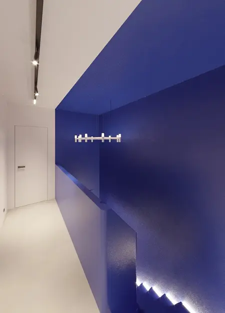 Korytarz z niebieskimi ścianami, oświetleniem LED w stylu industrialnym, minimalistycznym i nowoczesnym.