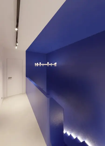 Korytarz z niebieskimi ścianami, oświetleniem LED w stylu industrialnym, minimalistycznym i nowoczesnym.