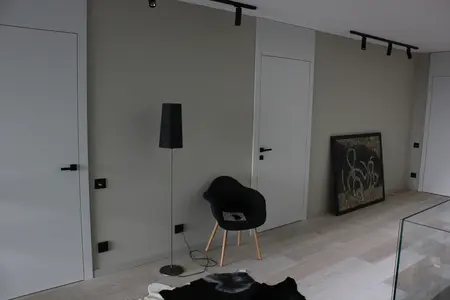 Minimalistyczne wnętrze z czarną lampą, białymi drzwiami i nowoczesnym wystrojem.