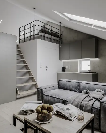 Wnętrze z aneksem kuchennym, szarym sofa i loftowym łóżkiem