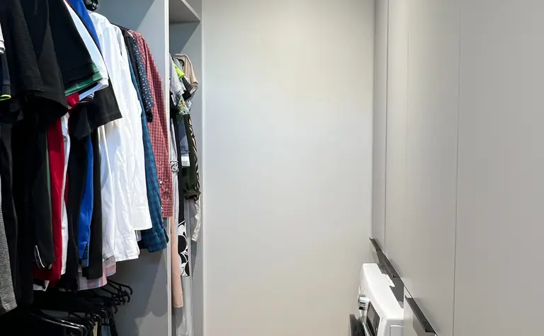 Garderoba w stylu nowoczesnym i soft minimalizm, z szarymi szafkami i drewnianą podłogą.