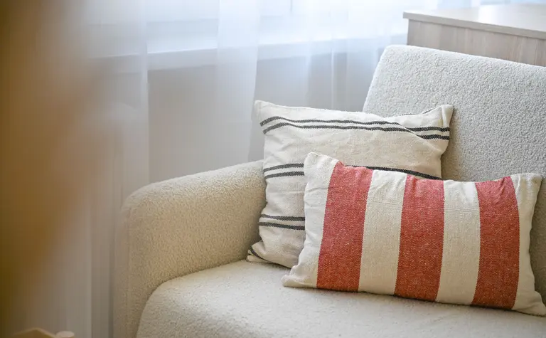 Sofa w stylu japandi z poduszkami w paski i jasnym tłem.