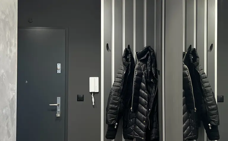 Nowoczesny przedpokój w soft minimalizmie z szarymi ścianami i lustrami.