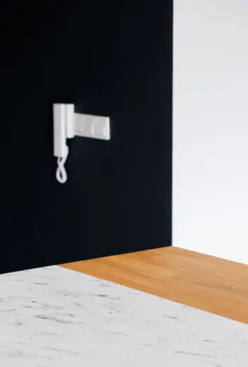Minimalistyczne wnętrze z białym blatem, czarną ścianą i drewnianym akcentem