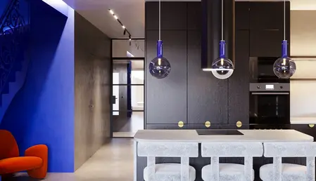 Wnętrze kuchni w stylu industrialnym, minimalistycznym i nowoczesnym z niebieską ścianą i czarnymi meblami.