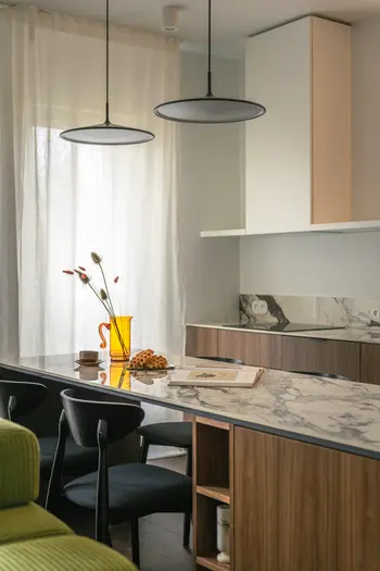 Wnętrze kuchni z eklektycznymi i minimalistycznymi akcentami, marmurowym blatem i drewnianymi detalami.