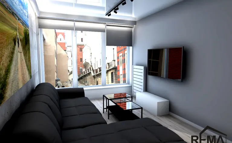 Wnętrze salonu z czarną sofą, szklanym stolikiem i nowoczesnym TV w stylu industrialnym.