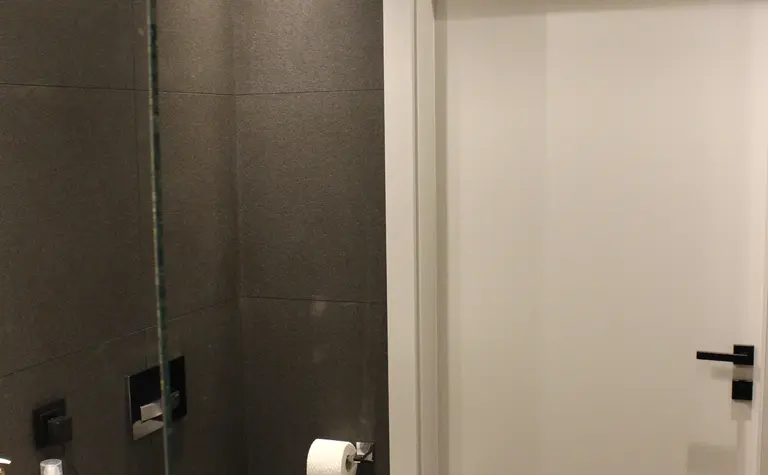 Nowoczesna łazienka z minimalistycznym designem, szare płytki, biała umywalka.
