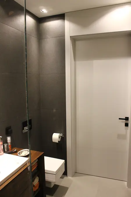 Nowoczesna łazienka z minimalistycznym designem, szare płytki, biała umywalka.