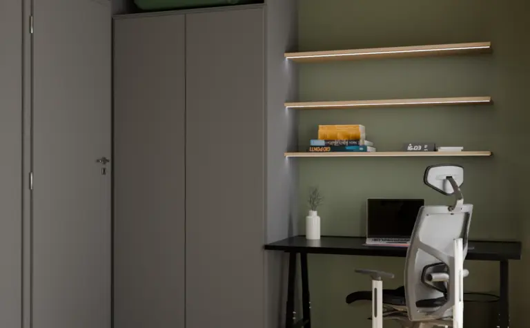 Gabinet w stylu soft minimalizmu z zieloną ścianą i szarym biurkiem.
