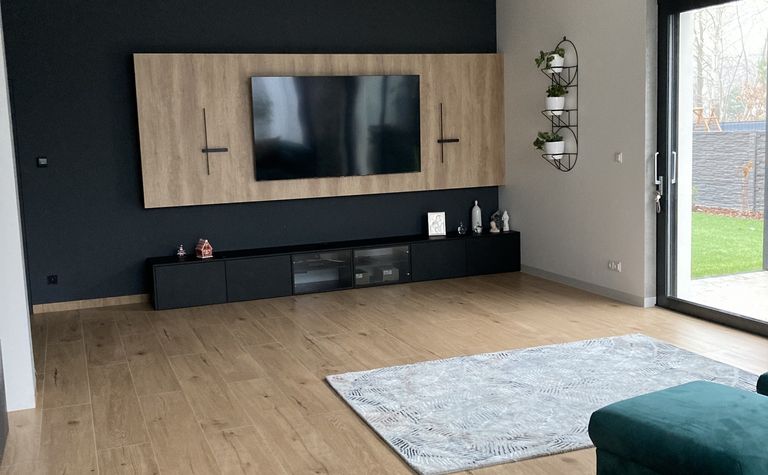 Wnętrze nowoczesnego salonu z telewizorem i drewnianymi elementami.
