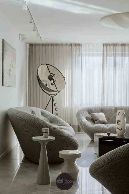 Minimalistyczne wnętrze salonu z szarymi meblami i nowoczesnym oświetleniem.
