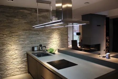 Wnętrze kuchni z minimalistycznym designem, kamienną ścianą i nowoczesnymi akcesoriami.