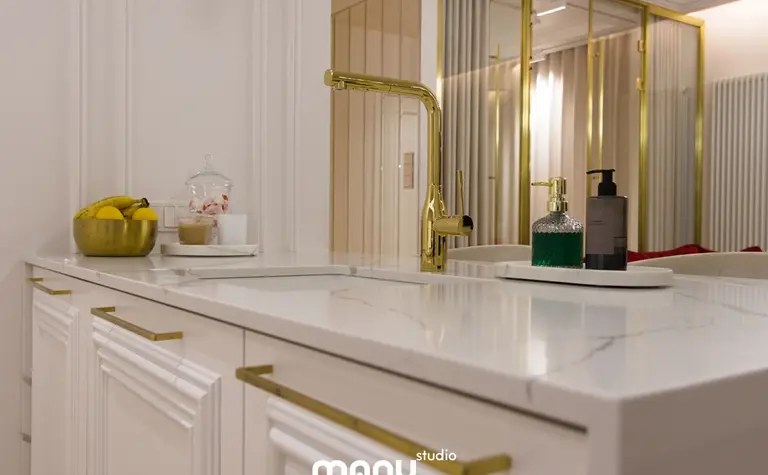 Nowoczesna łazienka z białą umywalką i złotymi elementami, tradycyjny design.