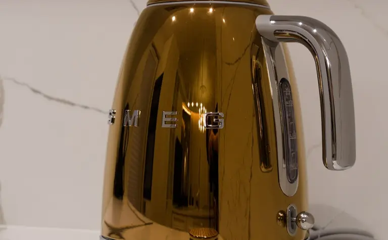 Czajnik SMEG w kolorze miedzianym na marmurowym blacie w nowoczesnej kuchni.