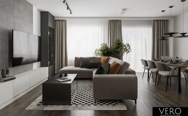 Wnętrze nowoczesnego salonu z minimalistycznym designem, szarymi meblami i zielonymi roślinami.