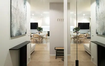 Nowoczesny przedpokój z drewnianą podłogą, jasnymi ścianami i obrazami w stylu quiet luxury.