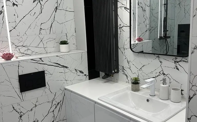 Nowoczesna łazienka z minimalistycznym designem, białe meble i czarne płytki.