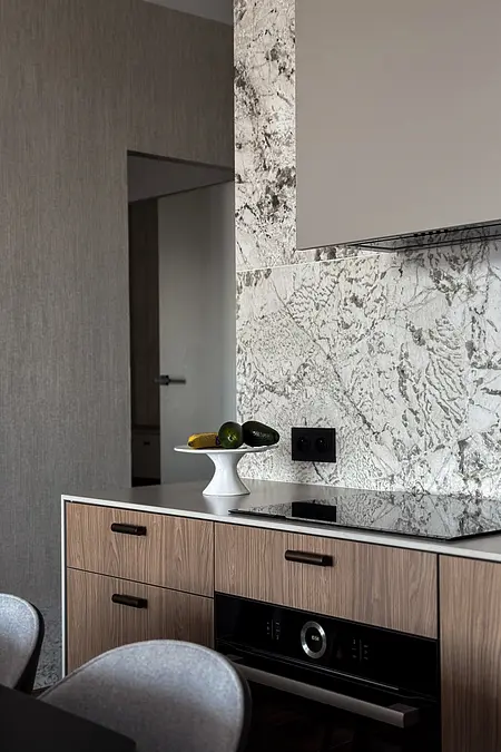 Nowoczesna kuchnia z drewnianymi meblami i szarym blatem, współczesne akcenty.