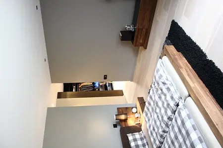 Sypialnia minimalistyczna z drewnianym łóżkiem, szarymi ścianami i nowoczesnymi detalami.