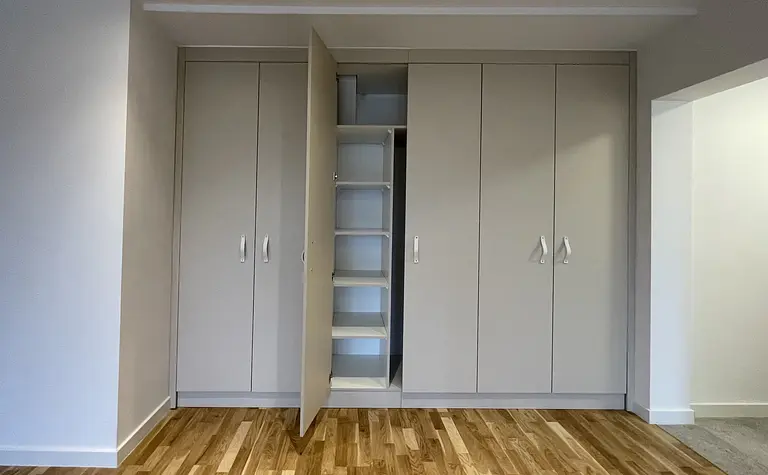 Garderoba z szarymi meblami, drewnianą podłogą w stylu eklektycznym, skandynawskim i współczesnym.