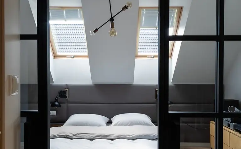 Wnętrze sypialni w stylu minimalistycznym z oknami dachowymi i nowoczesnym oświetleniem.