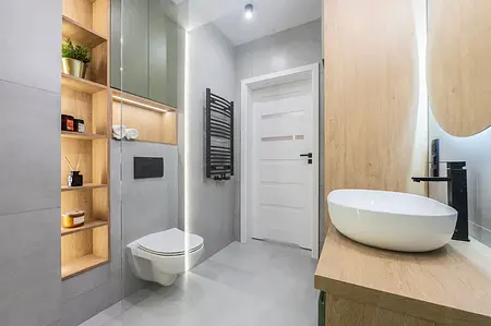 Wnętrze łazienki z drewnianymi meblami i nowoczesnymi detalami w stylu industrialnym i współczesnym.