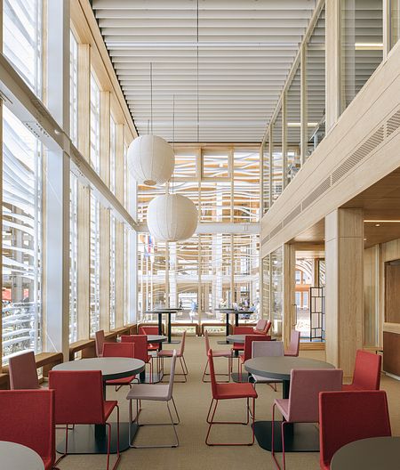 Nowoczesna kawiarnia z drewnianymi detalami i kolorowymi krzesłami, industrialny, minimalistyczny, boho, skandynawski, japandi.