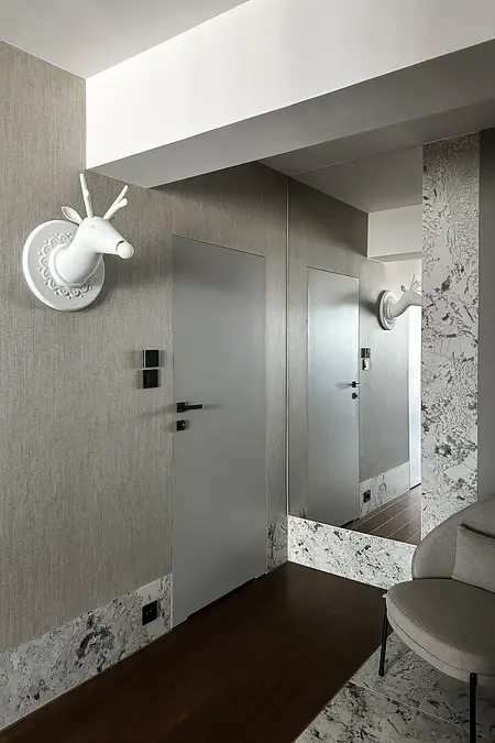 Przedpokój z szarymi ścianami, białym jeleniem i lustrem.