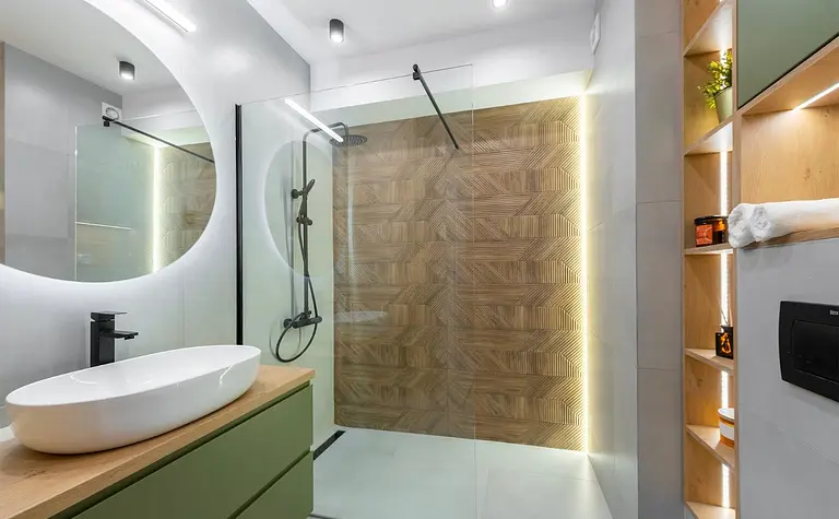Nowoczesna łazienka z drewnianą ścianą, zielonymi meblami i minimalistycznym designem.