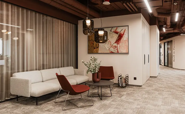 Wnętrze biura w stylu minimalistycznym z sofą, czerwonymi fotelami i nowoczesnym oświetleniem.