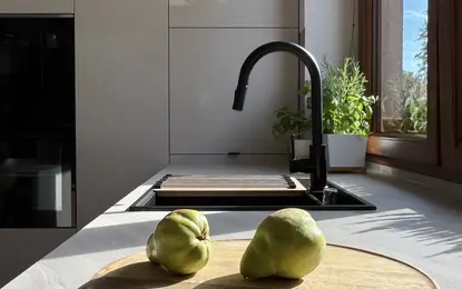 Wnętrze kuchni w stylu soft minimalizm z drewnianym blatem i roślinami.