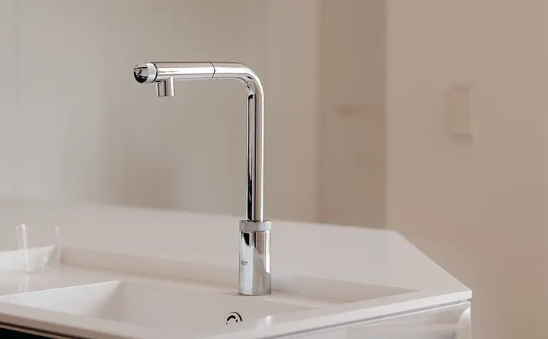Kuchnia w stylu minimalistycznym z białym blatem i czarnymi elementami.
