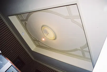 Sufit z ozdobnym motywem i lampą w eleganckim wnętrzu.