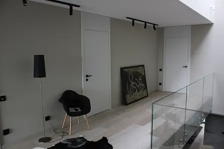 Minimalistyczne wnętrze z czarnym fotelem i dużą grafiką na ścianie, styl minimaluxe.