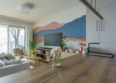 Wnętrze salonu z boho i współczesnym stylem, z roślinami i kolorowymi akcentami.