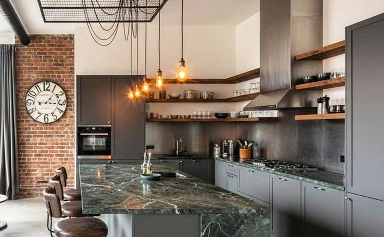 Kuchnia industrialna z ciemnym blatem, ceglaną ścianą i wiszącymi lampami.