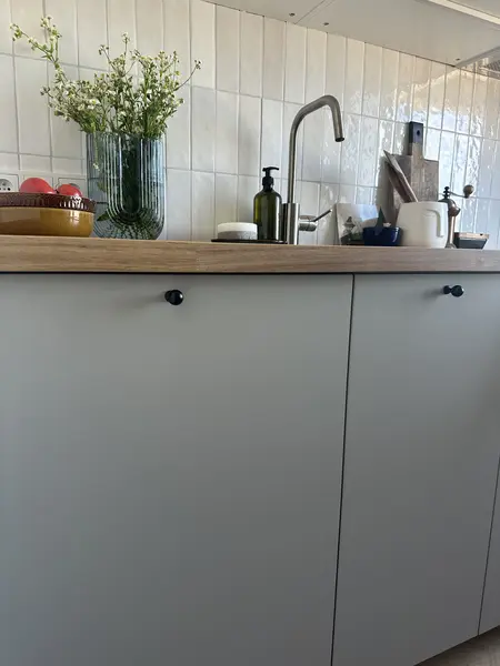 Kuchnia w stylu boho, skandynawskim i eklektycznym z szarymi meblami i drewnianym blatem.