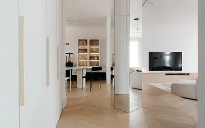 Eklektyczne i minimalistyczne wnętrze z białym stołem, czarnymi krzesłami i drewnianą podłogą.