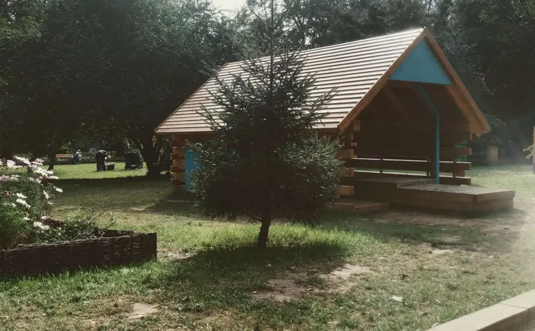 Domek ogrodowy z drewnianym tarasem otoczony zielenią, tradycyjny styl.