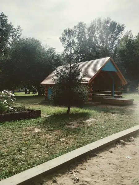 Domek ogrodowy z drewnianym tarasem otoczony zielenią, tradycyjny styl.