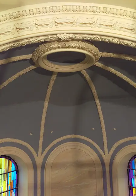Przestronny sufit z ozdobami i kolorowymi witrażami w tle.